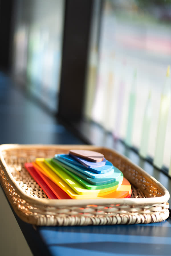 Un panier de formes arc-en-ciel en bois près de la fenêtre