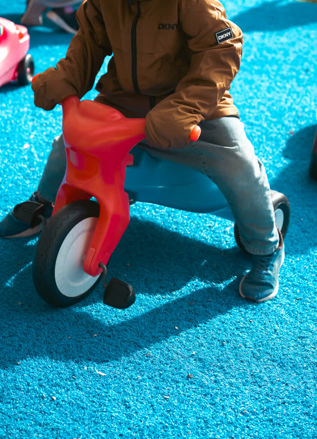 Un enfant en manteau sur un tricycle dans la cour