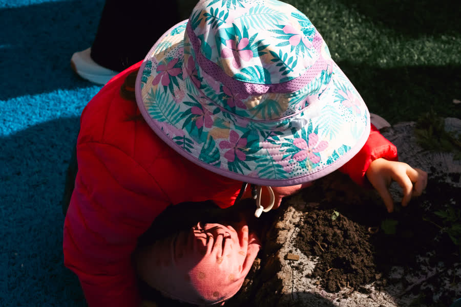 Un enfant au chapeau de soleil creuse dans le jardin